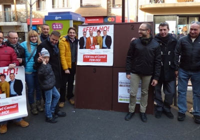 La candidatura d'Encamp al costat del primer cartell enganxat a la plaça del Consell